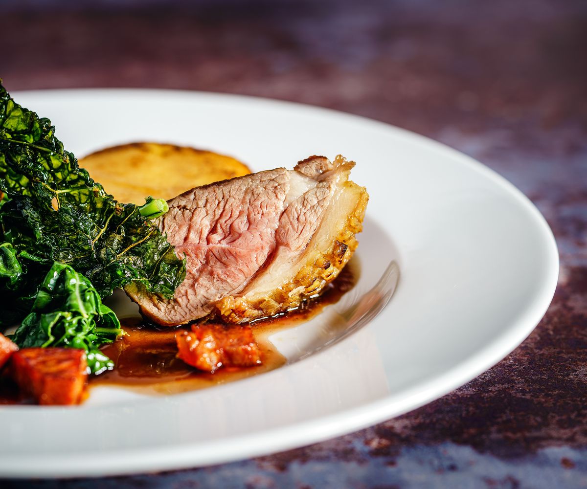 Roast meat with greens on a white plate