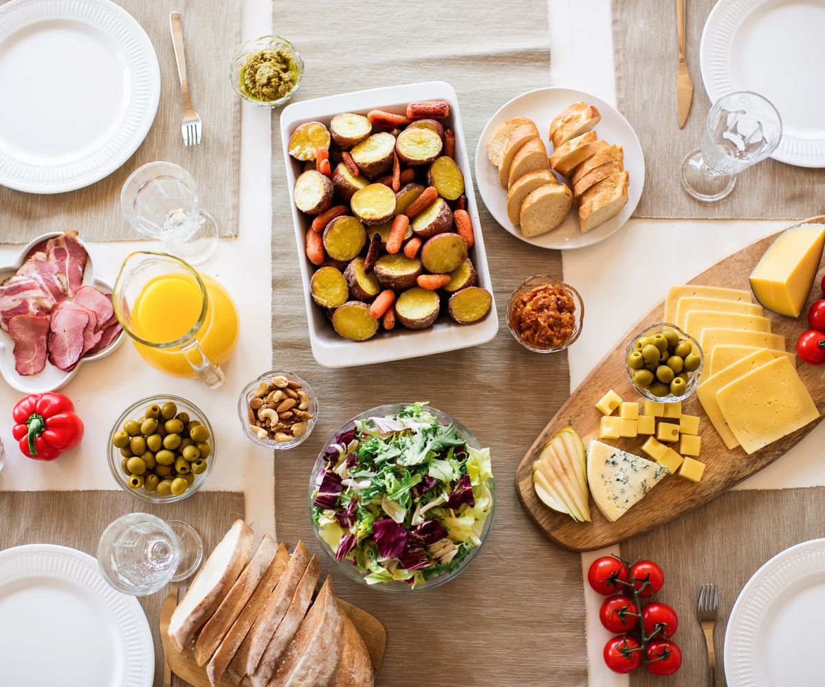 A table spread with bread, cheese, fruit and salad
